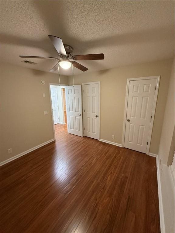 unfurnished bedroom featuring ceiling fan, dark hardwood / wood-style floors, and a textured ceiling