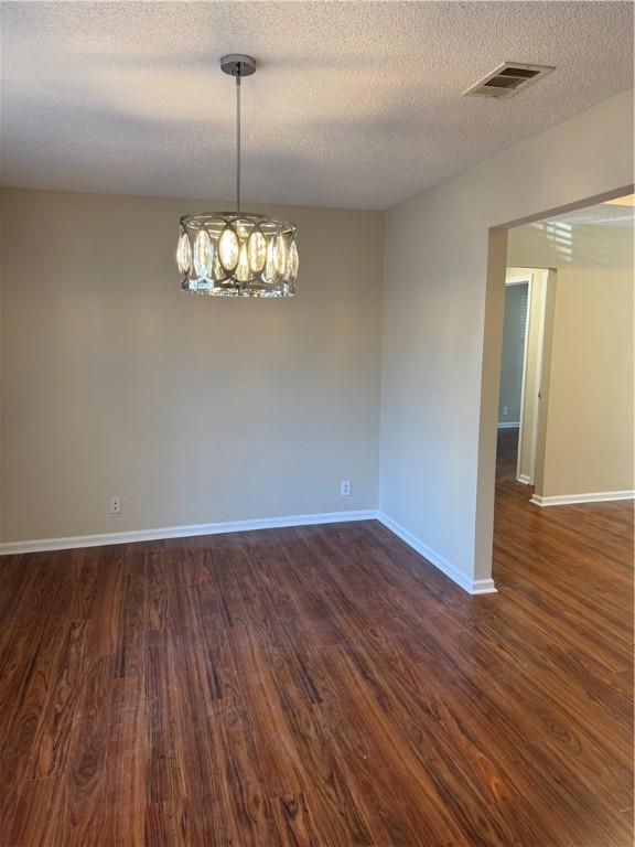 unfurnished room featuring dark hardwood / wood-style flooring, a notable chandelier, and a textured ceiling