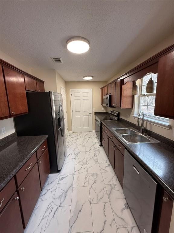 kitchen with appliances with stainless steel finishes, sink, and a textured ceiling