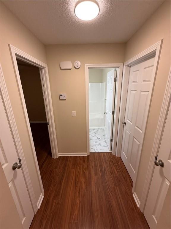 corridor featuring dark wood-type flooring and a textured ceiling