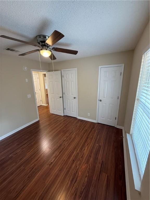 unfurnished bedroom featuring ceiling fan, dark hardwood / wood-style floors, and a textured ceiling