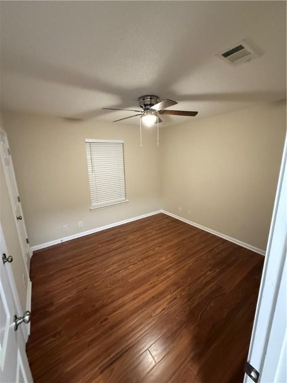 empty room with ceiling fan and dark hardwood / wood-style flooring