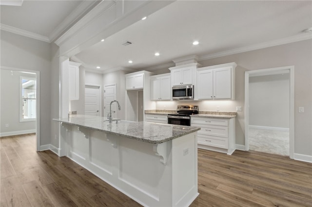 kitchen featuring stainless steel appliances, light stone countertops, a breakfast bar area, and white cabinets