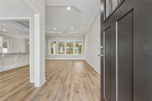 entrance foyer featuring crown molding, ceiling fan, light hardwood / wood-style floors, and a tray ceiling