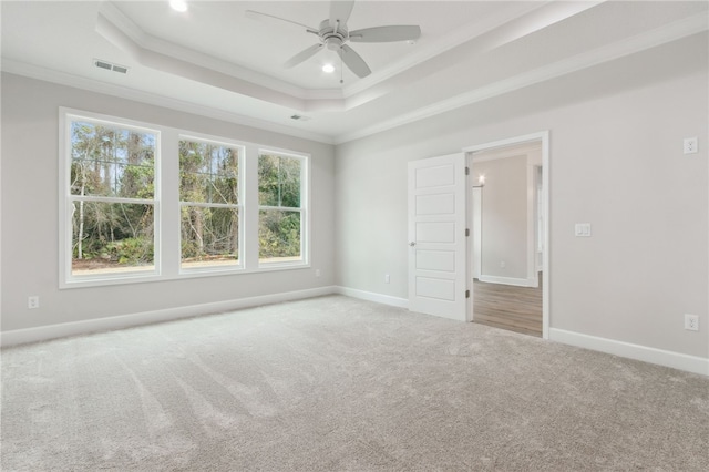 carpeted empty room featuring a tray ceiling, ornamental molding, and ceiling fan