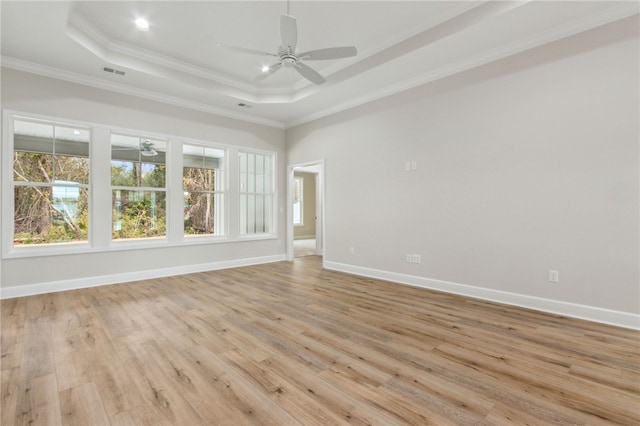 unfurnished room featuring light hardwood / wood-style floors, ornamental molding, and a raised ceiling