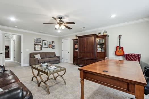 living room featuring light colored carpet, baseboards, crown molding, and ceiling fan