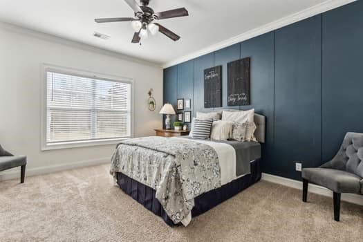 bedroom with visible vents, crown molding, baseboards, carpet, and a ceiling fan