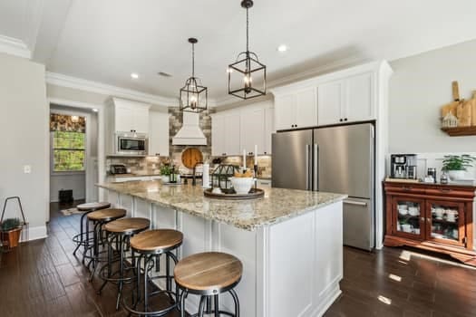 kitchen with appliances with stainless steel finishes, ornamental molding, dark wood-style flooring, and white cabinetry