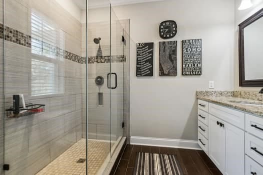 bathroom with vanity, wood finished floors, baseboards, and a stall shower