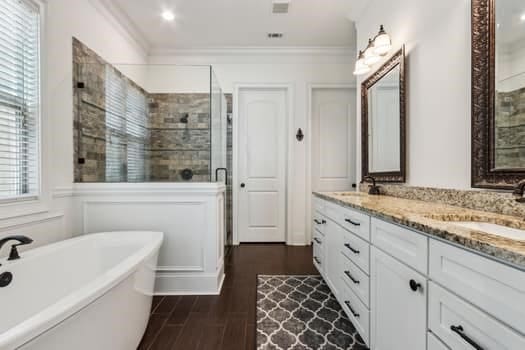 full bath with a freestanding tub, a stall shower, a sink, crown molding, and double vanity