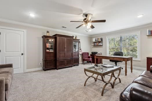 office space featuring crown molding, a ceiling fan, baseboards, and light carpet