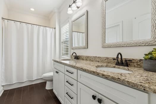 full bath featuring double vanity, toilet, wood finished floors, and a sink