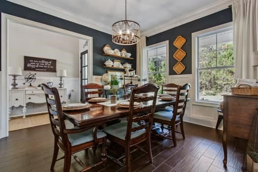 dining area with plenty of natural light, crown molding, an inviting chandelier, and a wainscoted wall