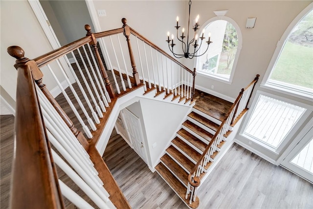 stairs with wood-type flooring and an inviting chandelier