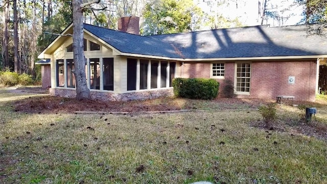 back of house featuring a sunroom and a lawn