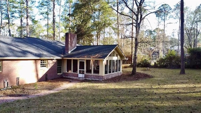 rear view of house with a yard and a sunroom