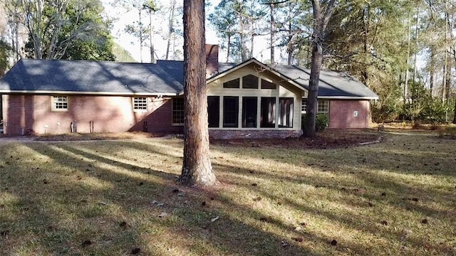 rear view of house featuring a yard and a sunroom