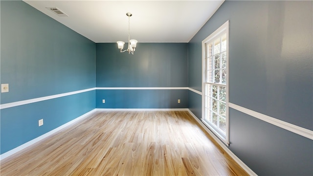 spare room with a notable chandelier and light hardwood / wood-style flooring