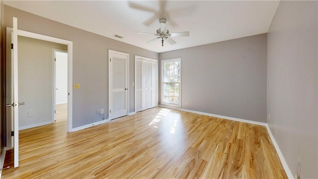 unfurnished bedroom with multiple closets, ceiling fan, and light wood-type flooring