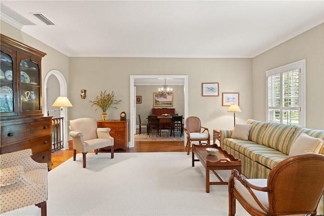 living area with light wood finished floors, visible vents, an inviting chandelier, and crown molding