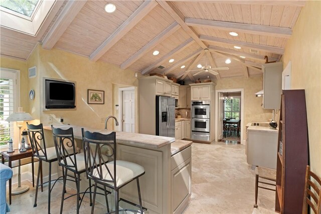kitchen featuring a peninsula, appliances with stainless steel finishes, a breakfast bar area, and lofted ceiling with skylight