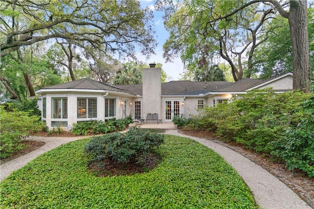 back of house featuring a patio area, french doors, stucco siding, and a chimney