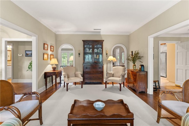living area with crown molding, visible vents, arched walkways, and wood finished floors