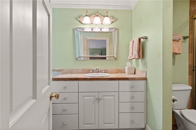 bathroom with vanity, crown molding, and toilet
