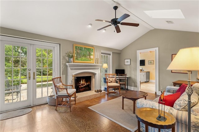 living room with wood finished floors, ceiling fan, visible vents, and a tile fireplace