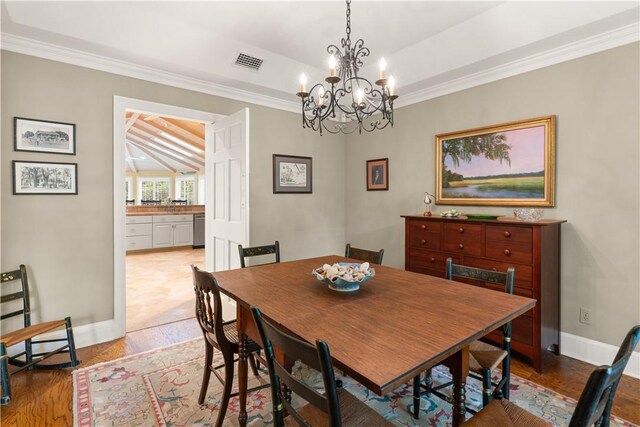 dining space featuring visible vents, baseboards, an inviting chandelier, ornamental molding, and wood finished floors
