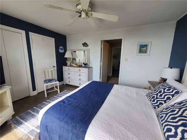 bedroom featuring ceiling fan, dark wood-type flooring, and two closets