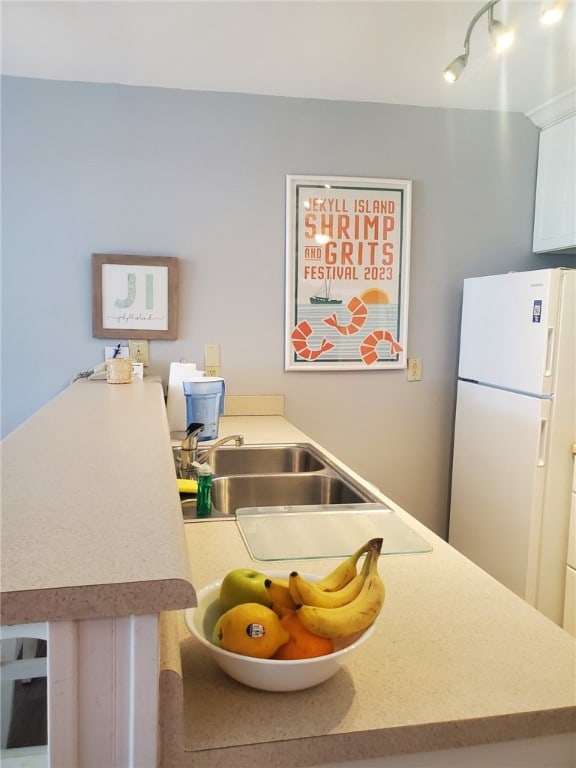 kitchen with white fridge, kitchen peninsula, and sink