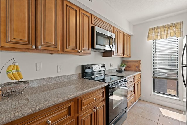 2502 Demere Rd Unit 3, Saint Simons Island, GA 31522 - kitchen featuring black electric range oven, stainless steel microwave, brown cabinetry, and light tile patterned floors