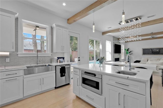 kitchen with stainless steel dishwasher, decorative light fixtures, white cabinetry, and sink