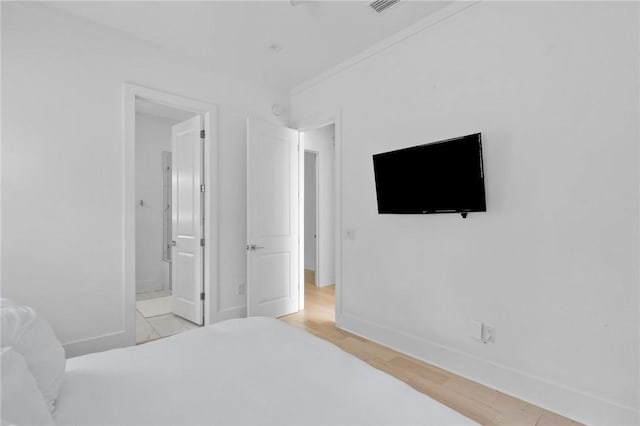 bedroom featuring ensuite bathroom and light hardwood / wood-style flooring