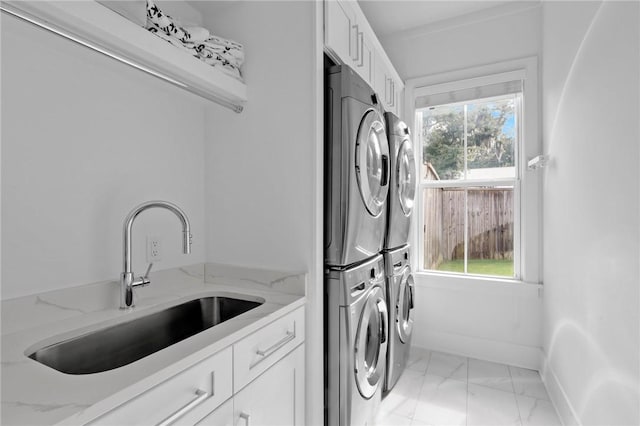 clothes washing area featuring cabinets, stacked washer / drying machine, and sink