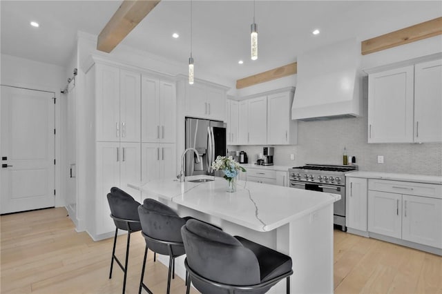 kitchen with hanging light fixtures, white cabinetry, appliances with stainless steel finishes, beam ceiling, and custom range hood