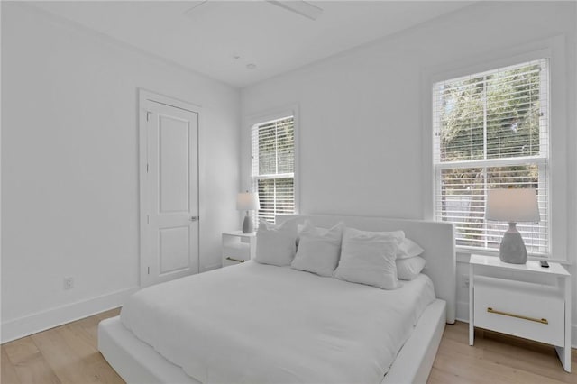 bedroom with multiple windows, light wood-type flooring, and ceiling fan