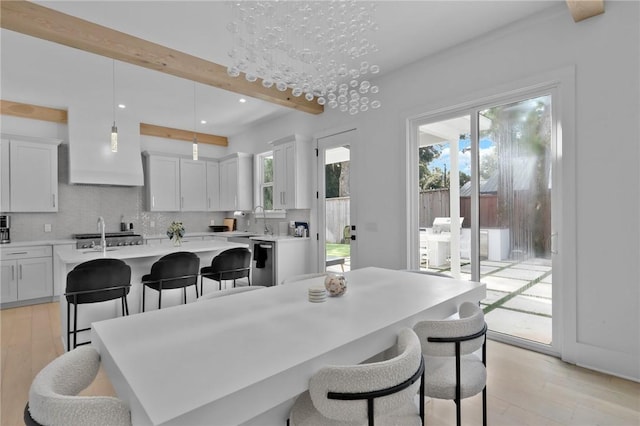 dining room with beam ceiling, light hardwood / wood-style flooring, and sink