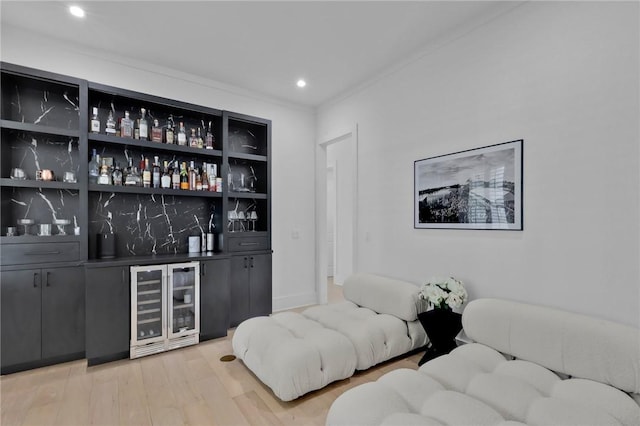 bar with light wood-type flooring, beverage cooler, and ornamental molding