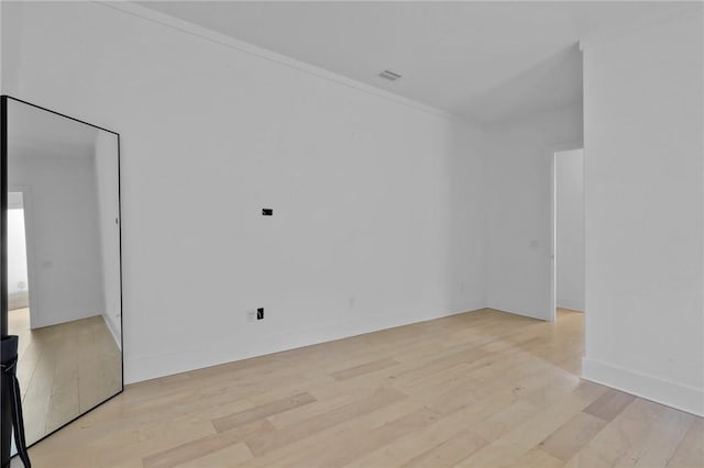 unfurnished room with ornamental molding and light wood-type flooring