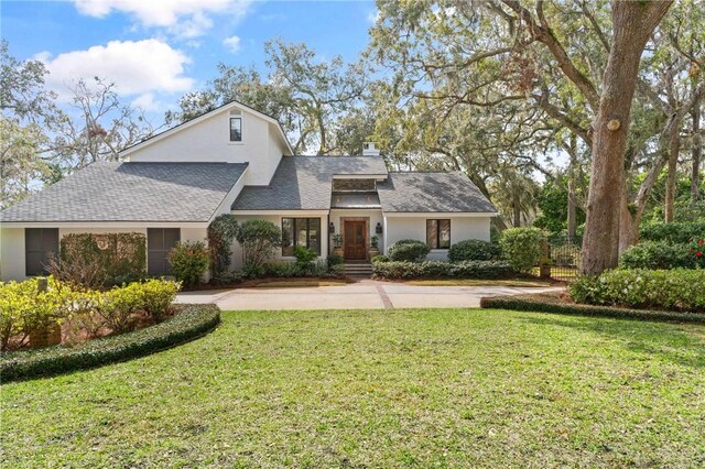 view of front of home with stucco siding, roof with shingles, and a front lawn