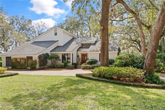 view of front of house featuring stucco siding, a shingled roof, and a front yard