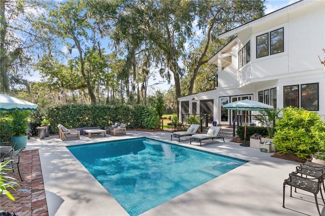 pool featuring an outdoor living space, a patio area, and a sunroom