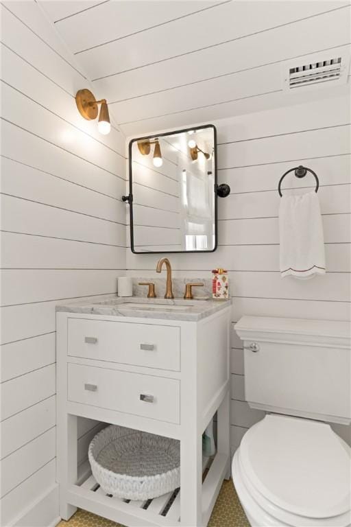 half bath with wooden walls, toilet, wooden ceiling, and vanity