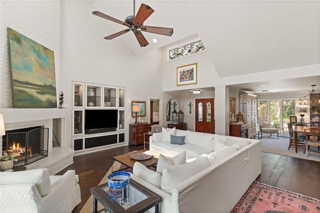 living room featuring ceiling fan with notable chandelier, dark wood-style floors, recessed lighting, a high ceiling, and a fireplace