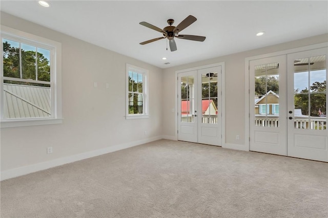 carpeted spare room featuring ceiling fan, french doors, and plenty of natural light