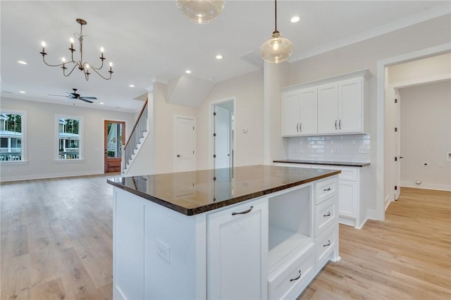 kitchen featuring white cabinets, ceiling fan, light wood-type flooring, decorative light fixtures, and a kitchen island