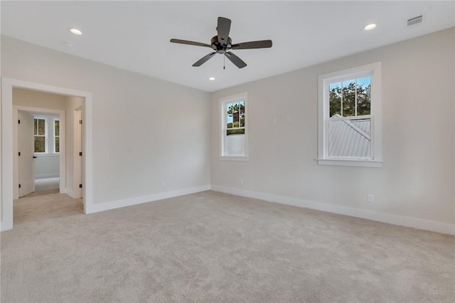 spare room with light carpet, ceiling fan, and a healthy amount of sunlight